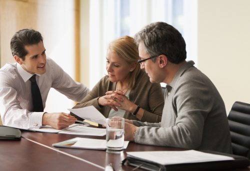 couple sitting at a table going over paperwork with an advisor