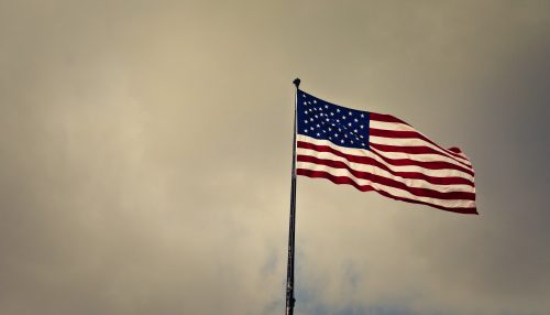 American flag flying on flagpole with foggy background
