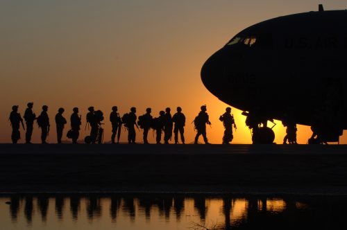 silhouette of military members entering an airplane