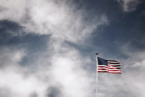 American flag flying on flagpole with partly cloudy sky in background